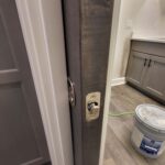 Close-up of a pocket door installation showing the hardware and trim details, indicating the work is finished but unpainted.