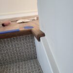 White shoe molding installed at base of wood baseboard over carpet transition.