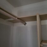 This photo shows a completed wire shelf installation in a closet, highlighting the support rod and shelf alignment.
