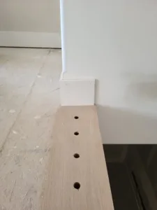 Closet shelf with drilled support holes mounted on a wall bracket, unfinished stage