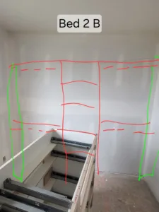 Closet wall marked with layout tape for planned shelf and rod placement, drywall stage.