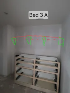 Closet wall with layout tape markings above a raw wood shelf support frame under construction.