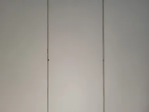 White vertical seams and small hardware marks on a wall, during closet door installation.