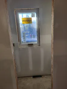 Window unit installed in an unfinished drywall opening, protective tape and label still in place.