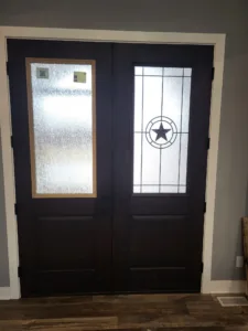 Black double doors with frosted glass lites and a star medallion, installed with white casing.