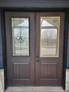 Stained double entry doors with etched star glass panel and lockset hardware, completed