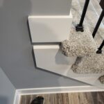 This photo shows a completed trim installation of skirt boards at the base of a staircase, highlighting the clean lines and craftsmanship.
