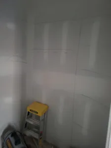 Empty room with finished white walls, faint pencil markup on one wall, and a step ladder present.