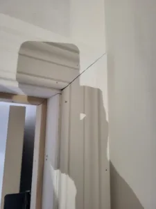 Painted door jamb extension with a curved return at a wall corner