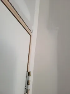 Door jamb with hinge installed in a drywall opening, unfinished, ready for door slab and casing.