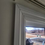 Painted white window casing installed around exterior window opening with mitered corners.