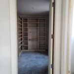 Custom built-in closet shelving with face-frame cubbies, primed door frame, ready for paint.