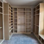 Custom built-in closet shelving with face-frame cubbies, raw wood ready for paint.
