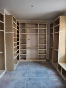 Extensive unfinished closet shelving with face frame cubbies on three walls, raw wood ready for paint