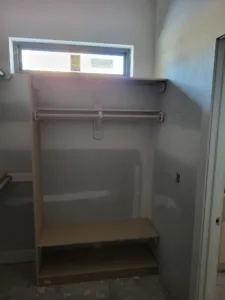 Closet shelving with a hanging rod, wood shelf, and support bracket, installed near a window.