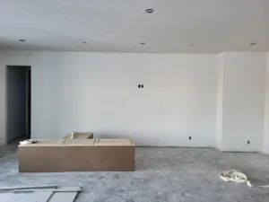 Empty drywalled room with recessed lighting and a small wood structure being assembled at one wall.