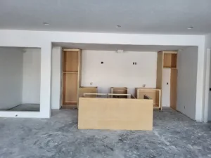 Kitchen island cabinet boxes installed mid room, surrounded by base cabinets, drywall stage.