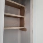 Custom built-in shelving with three wood shelves and cleats, raw wood ready for finish.