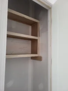 Small built in shelving with three wood shelves and cleats, raw wood ready for paint