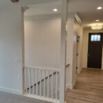 White painted safety gate installed in doorway opening with vertical spindles and functional latch.