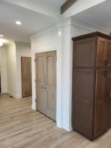Stained wood decorative header beam above double doors, with white crown molding and painted casing.