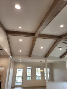 Dark stained ceiling beams forming a grid above a vaulted area with French doors