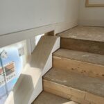 White-painted skirt board installed along stair opening with raw wood treads and risers ready for finish.