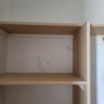 Raw particle board shelving unit with two shelves and dividers, unfinished and marked for installation. (Wrong Way)