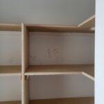 Raw wood closet shelving with two tiers, particle board shelves and 1x cleats, pre-paint stage with layout markings visible. (Wrong Way)