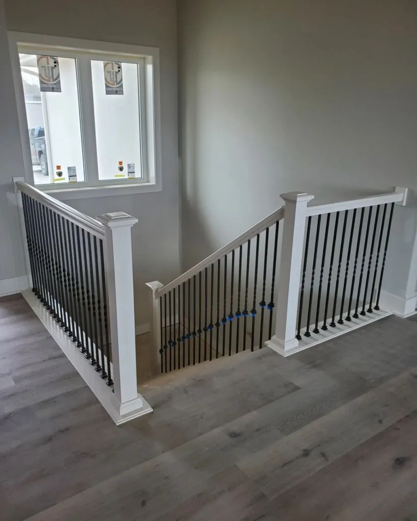 Metal balusters evenly spaced on a level run and a rake section between white newel posts