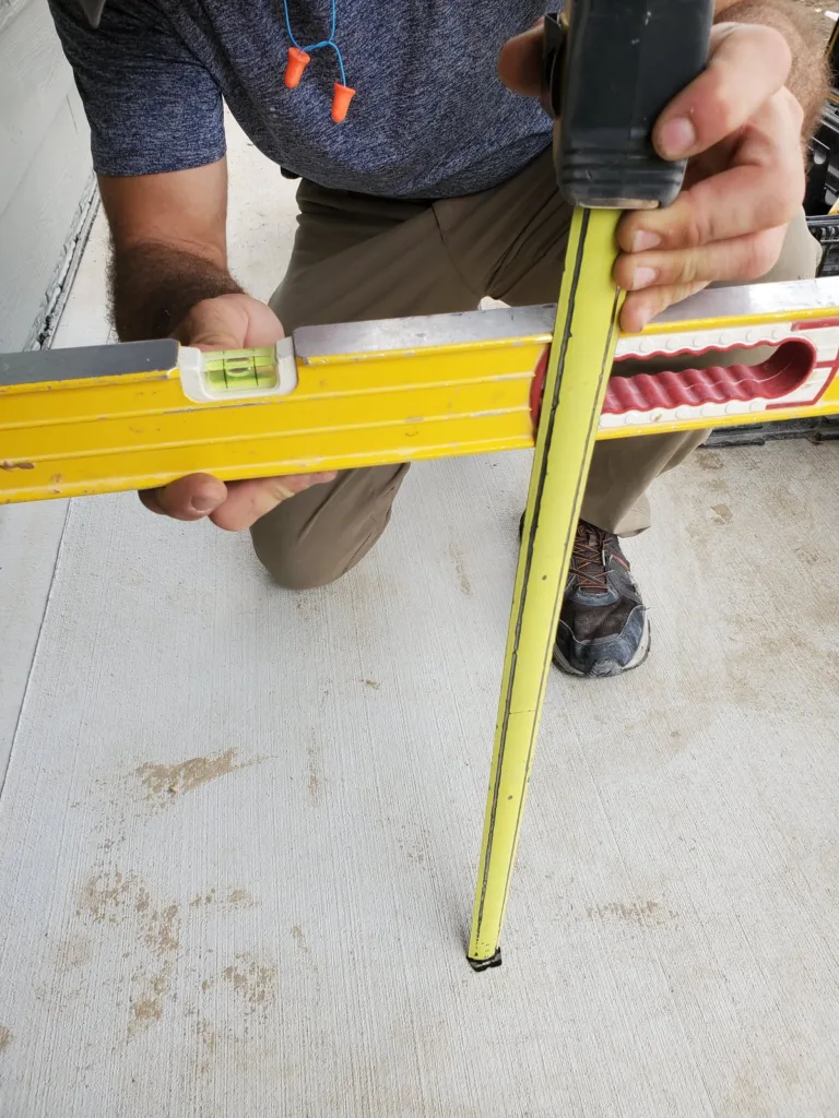 Level held out from the door with a tape run straight down to the patio slab to read the total rise