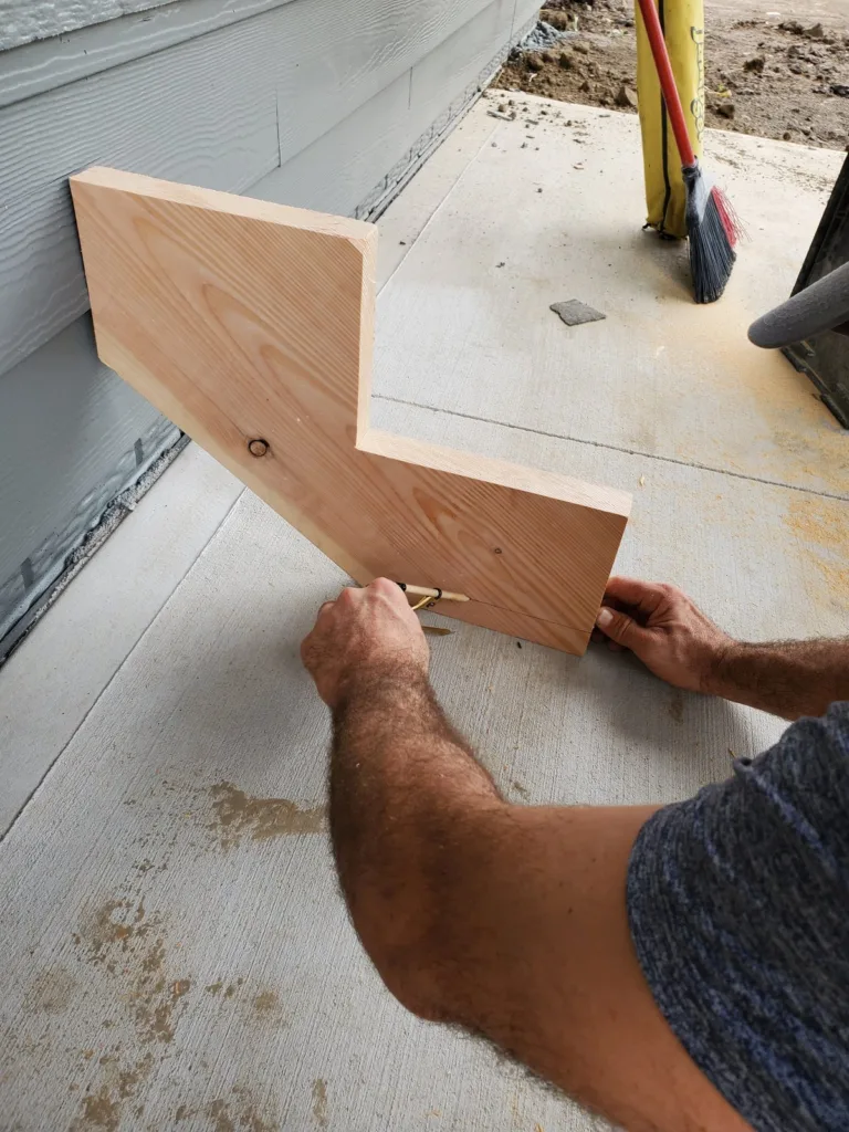 Stringer held against the house siding while a pencil scribes the slab line onto its bottom end