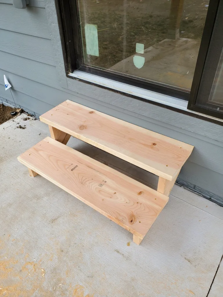 Finished cedar patio steps with two treads, three risers and open stringers below a sliding door